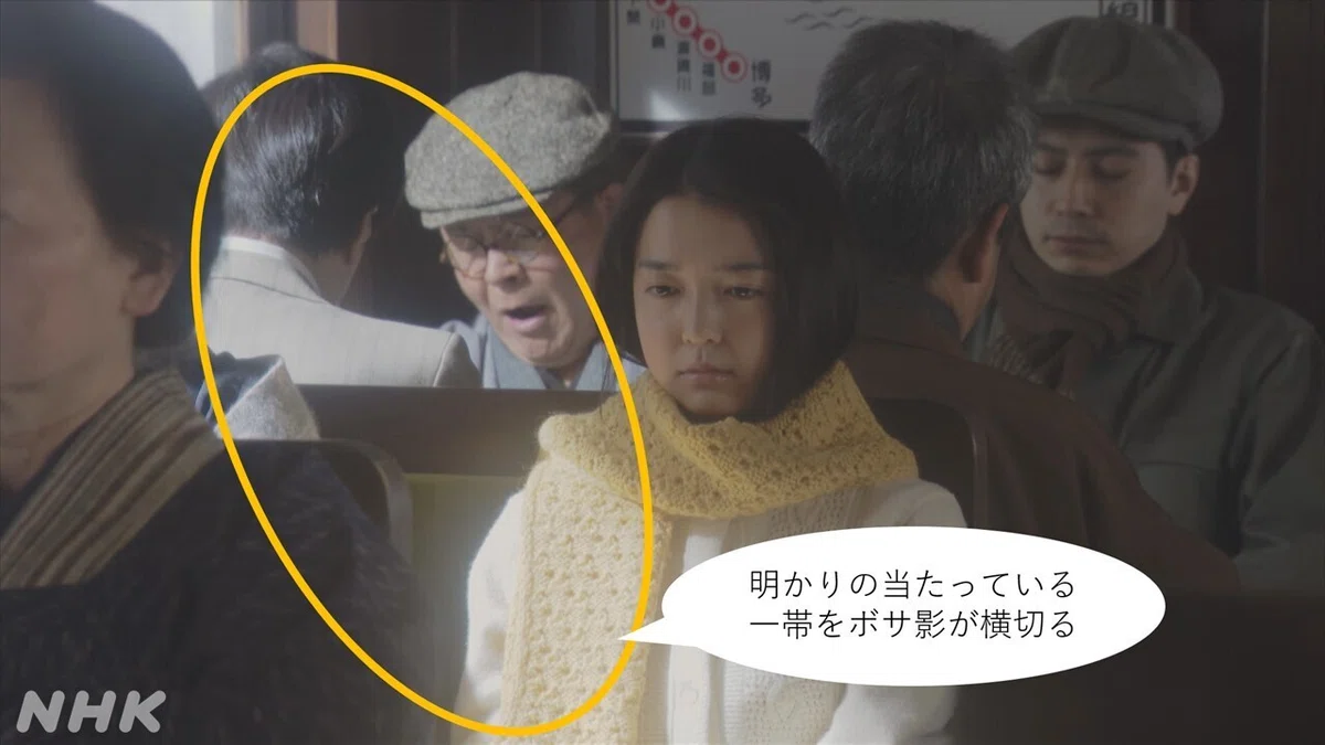劇中写真内:明かりの当たっている一帯をボサ影が横切る