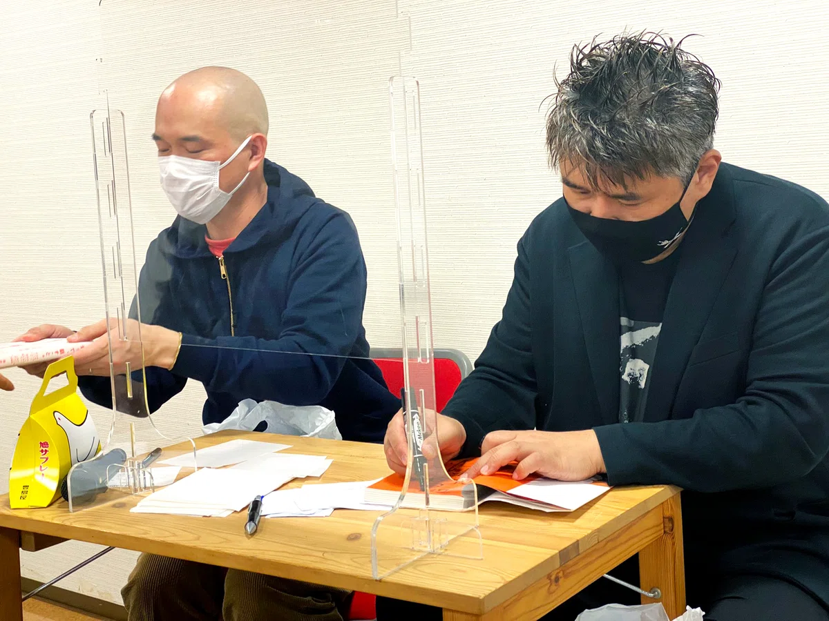 書籍にサインをする泰延さんと、サイン本を参加者へ手渡す今野さん