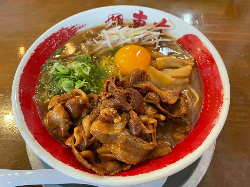 徳島ラーメンの写真。丼の中にもやし、青ネギ、メンマ、生卵、豚バラが入っており、茶色いスープが少し見えている。