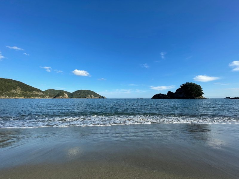 大浜海岸の晴れた日の写真。穏やかな海と海岸が写っている。