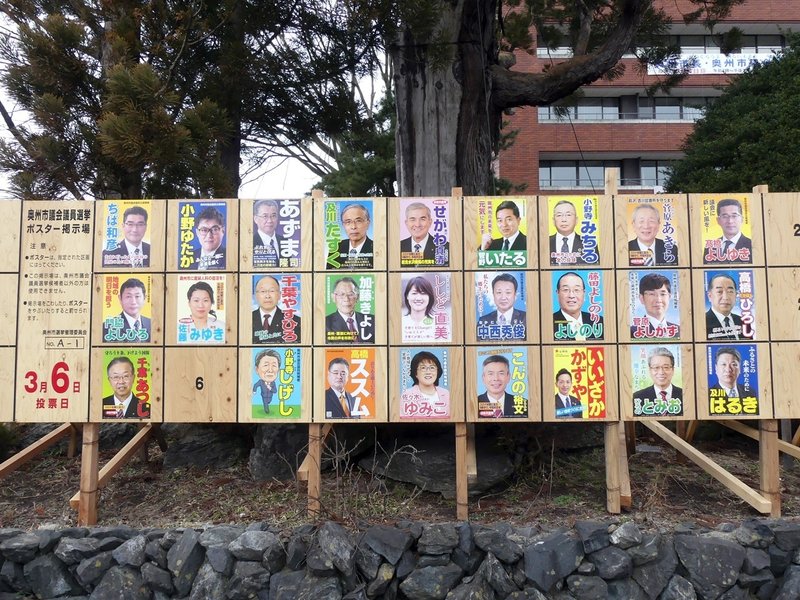 奥州市議選の選挙ボードの写真。２８人のポスターが並んでいる。