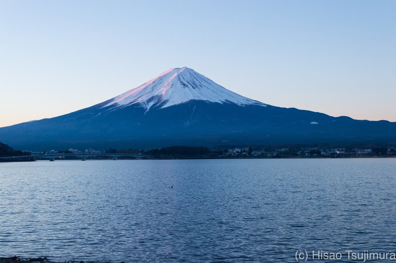 東側がわずかに赤く照らされている夜明けの冠雪した富士山