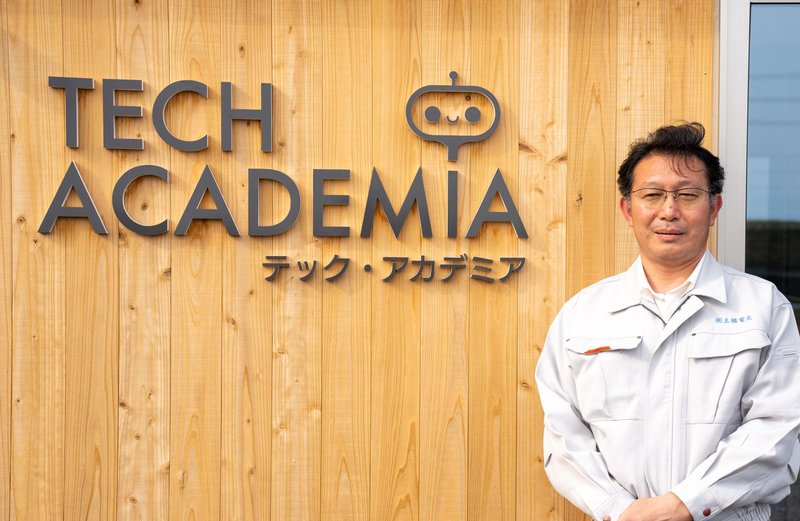 「テック・アカデミア」ロゴの前で
