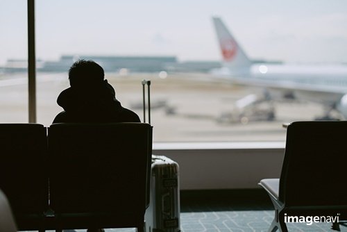 空港で飛行機を待つ人｜MakiEni / イメージナビ