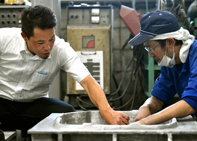 栄鋳造所の鈴木隆史代表取締役社長(左)=西夏生撮影