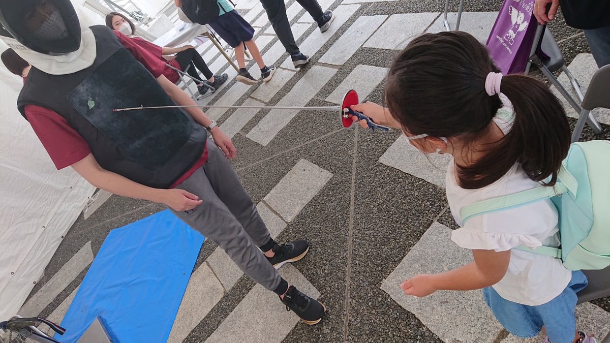 A girl performing a fencing sabre exercise and a member of the sports organization's staff