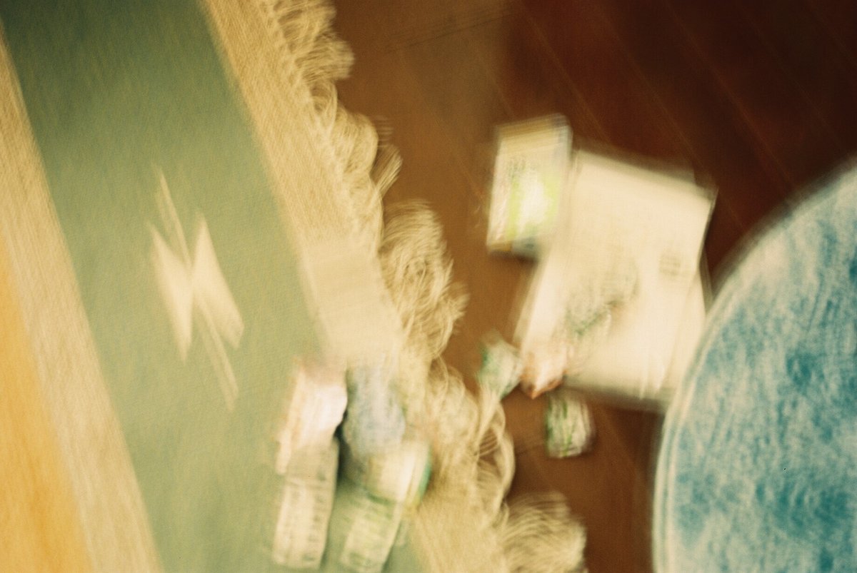 床に散らばった薬の空き殻のフィルム写真。かなりぶれている。