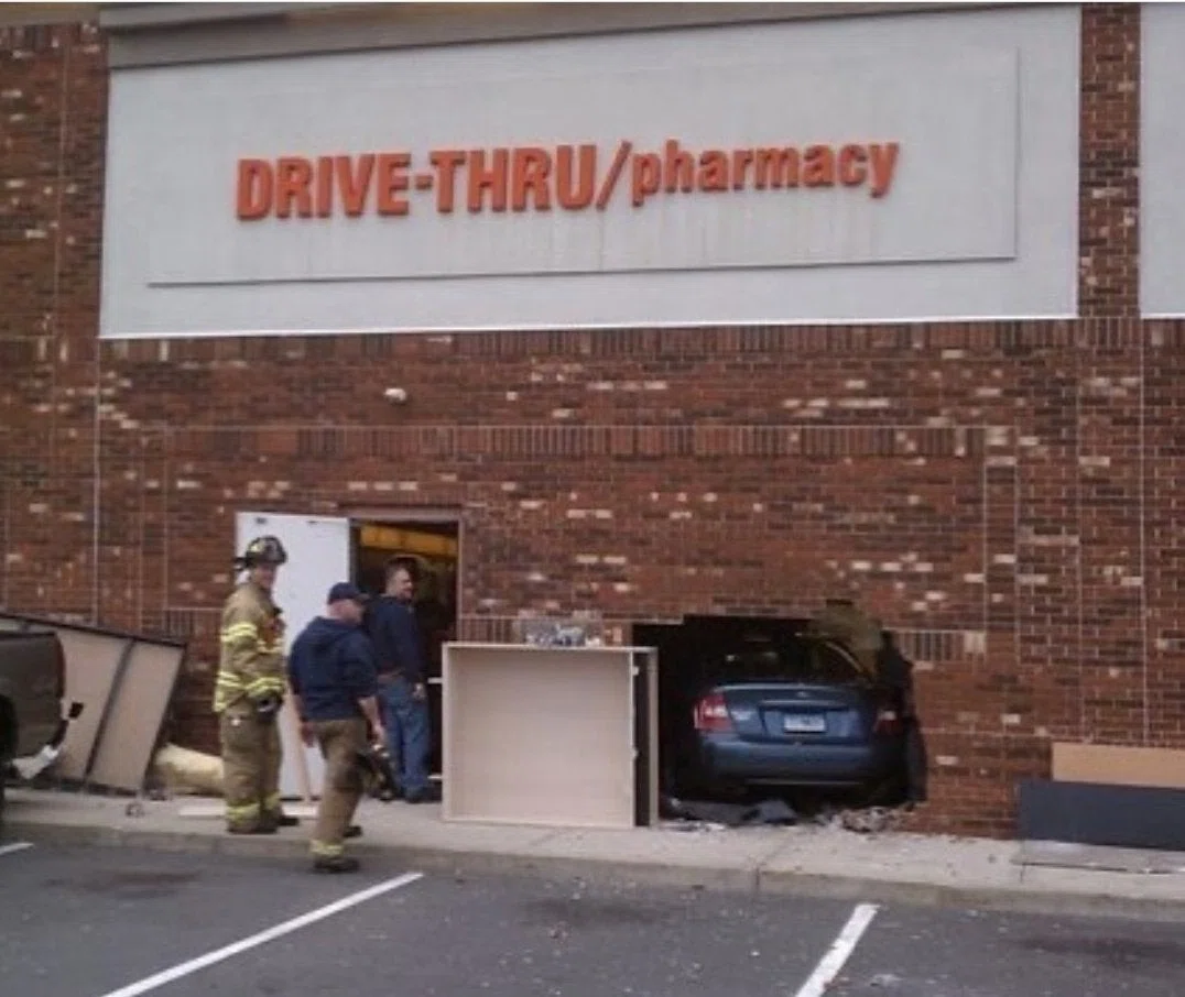 DRIVE-THRU/pharmacyという看板の店舗の壁に突っ込んでいる自動車の写真