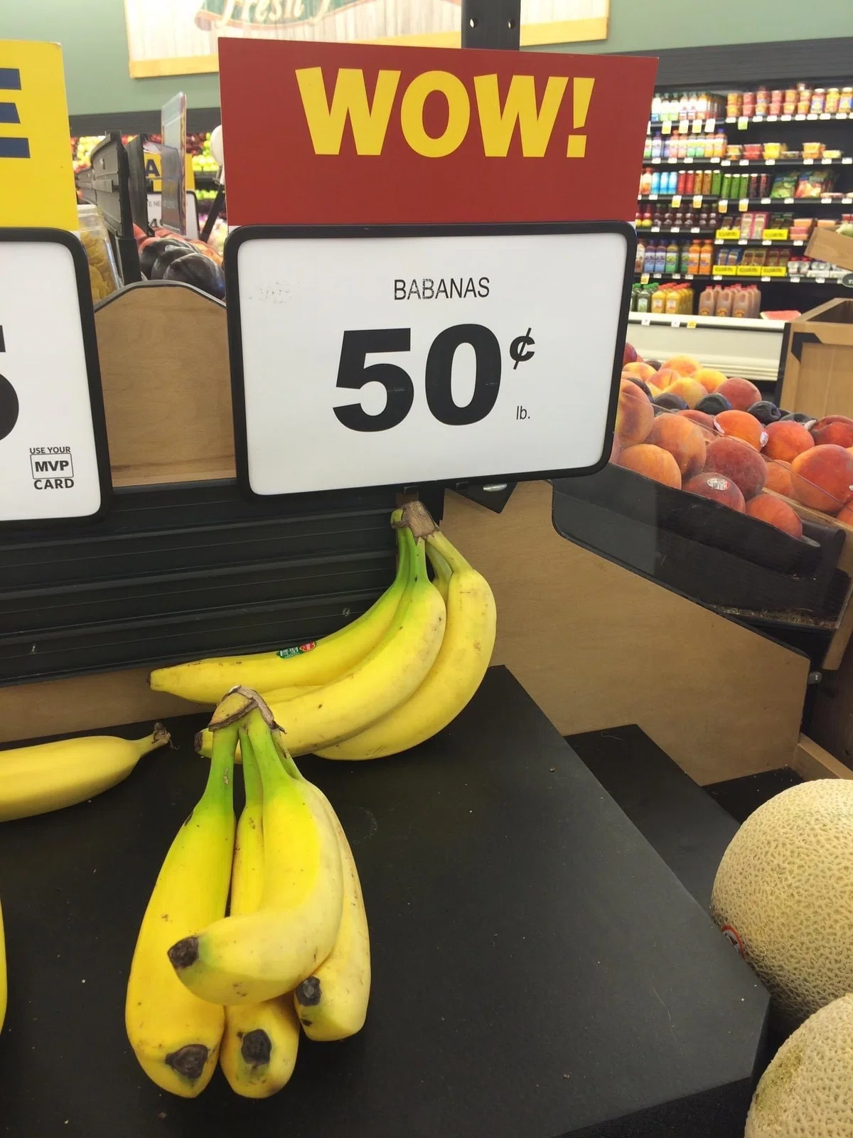 スーパーにバナナが陳列されており、その上に「WOW! BABANAS 50¢ lb.」と書かれている