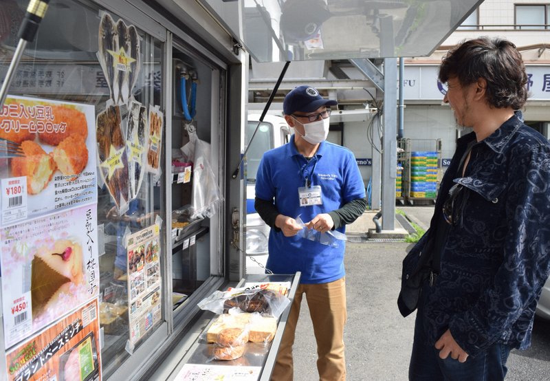 移動販売車の前で、社員と会話する小野篤人さん(右)=清水憲司撮影