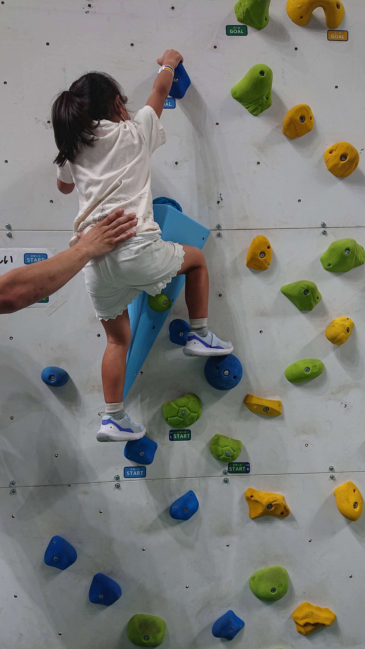 A girl trying her hand at bouldering with the support of staff