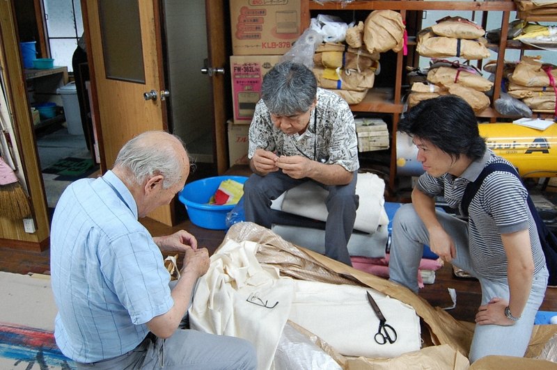 愛知県豊橋市の織物職人さんたちと話すエニシングの西村和弘さん（右）＝2010年