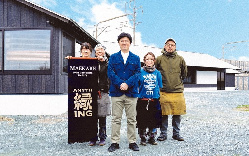 新工場で写真に納まるエニシングの西村和弘さん（中央）と社員たち＝同社提供