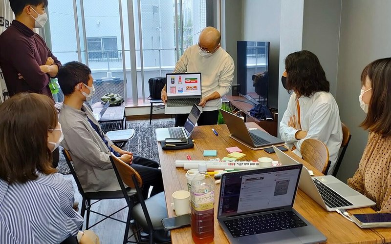 5人のメンバーがノートPCを見つめる写真