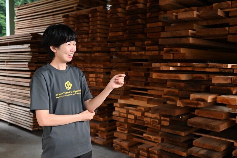 山共さんの木材置き場にて、木材について説明する葵さんの写真