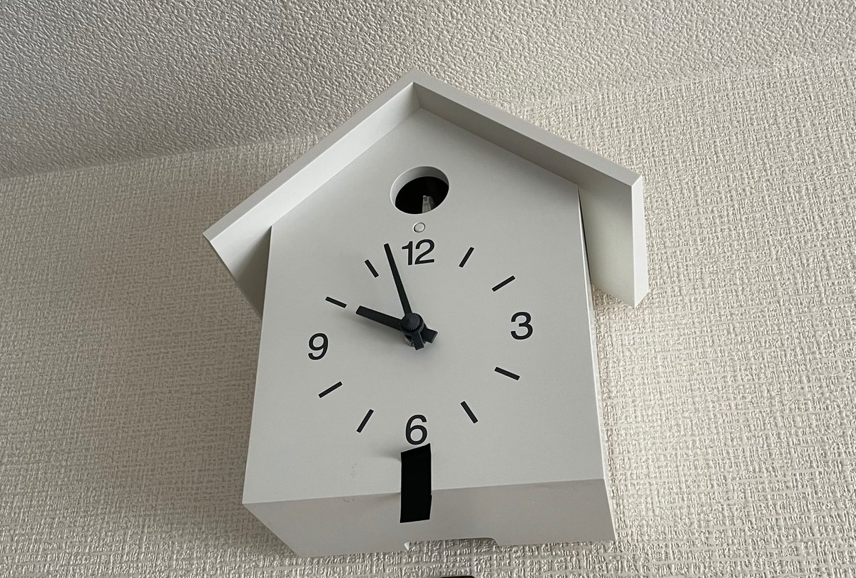 壁にかかっている無印良品の鳩時計。時計の下にある照度センサーに黒いマスキングテープが貼られている。