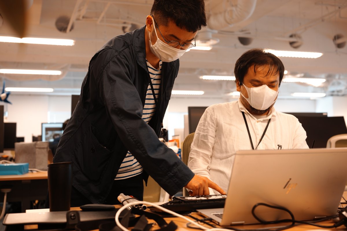 写真:awaさんが目を閉じて中根さんの点字ディスプレイを触っている様子