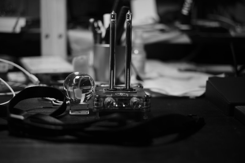 黒い机の上に水晶とガラス管型音量メーターが置かれている風景（モノクロ）