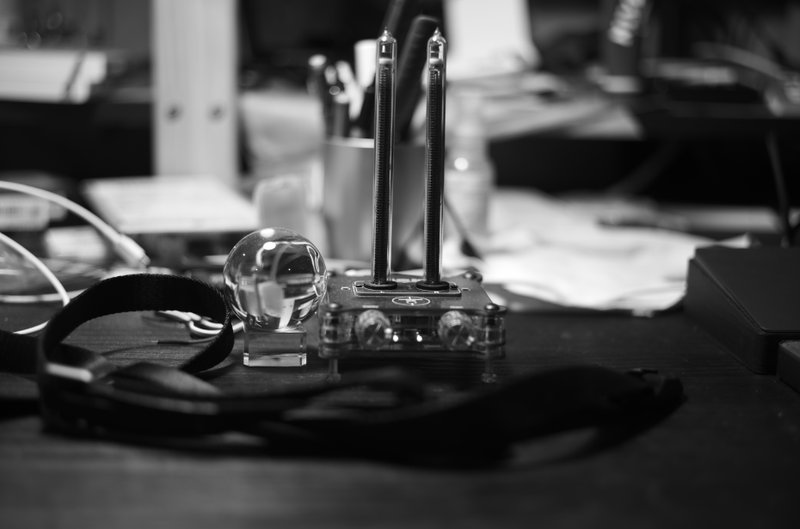 黒い机の上に水晶とガラス管型音量メーターが置かれている風景（モノクロ）