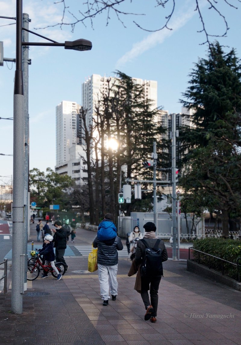 夕方、お父さんに肩車をしてもらっている男の子、自転車に乗る男の子たち、道を行く男性などの写真です。