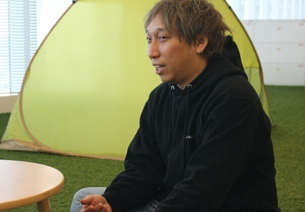 デジタル庁のエンジニアユニット長である松館がインタビューを受けている写真