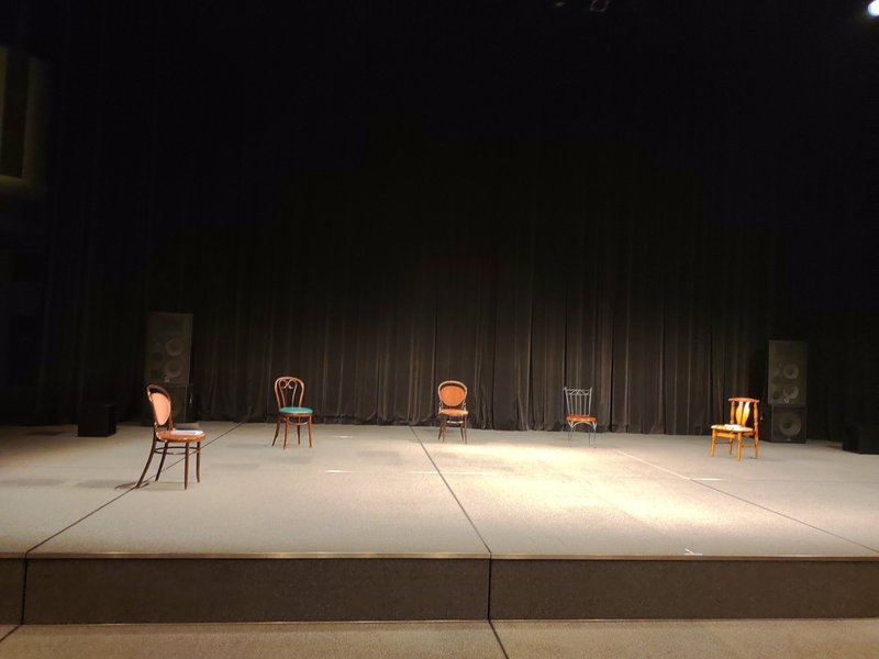 舞台上に椅子が５脚、半円状に並べてある写真。