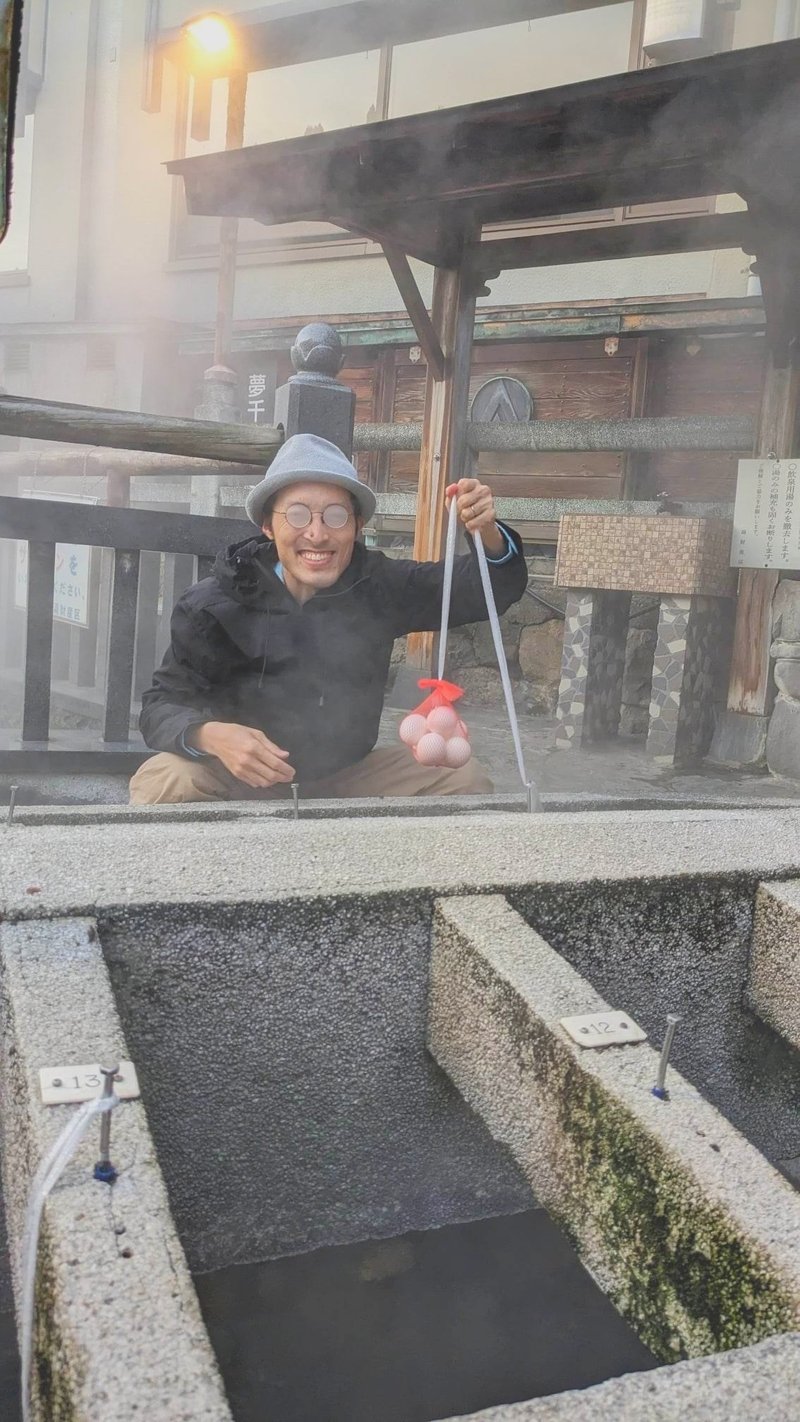 湯村温泉の荒湯で温泉たまごを作る男性