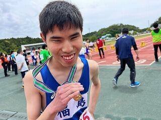 １００メートルで第１位に入賞し笑顔でメダルを手にする選手