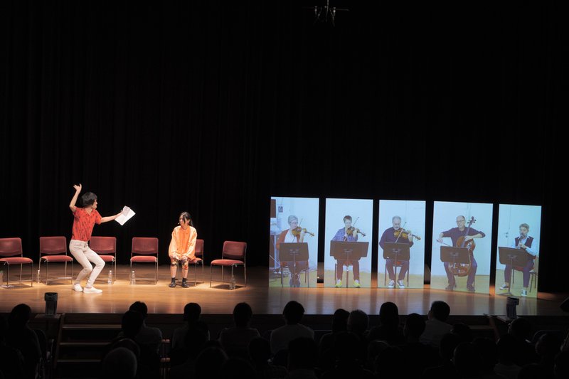 舞台左側に俳優２名、右側に等身大の映像パネルで映し出される演奏者のクラングフォルム・ウィーン５名