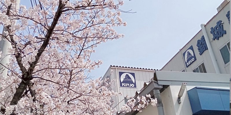 満開の桜と錦城護謨株式会社の本社外観