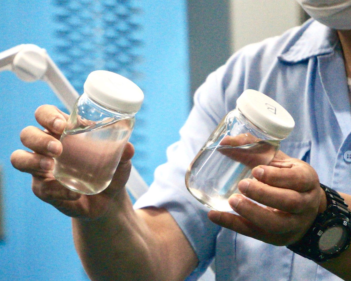 瓶に入った原料であるシリコーンゴムもって説明している様子