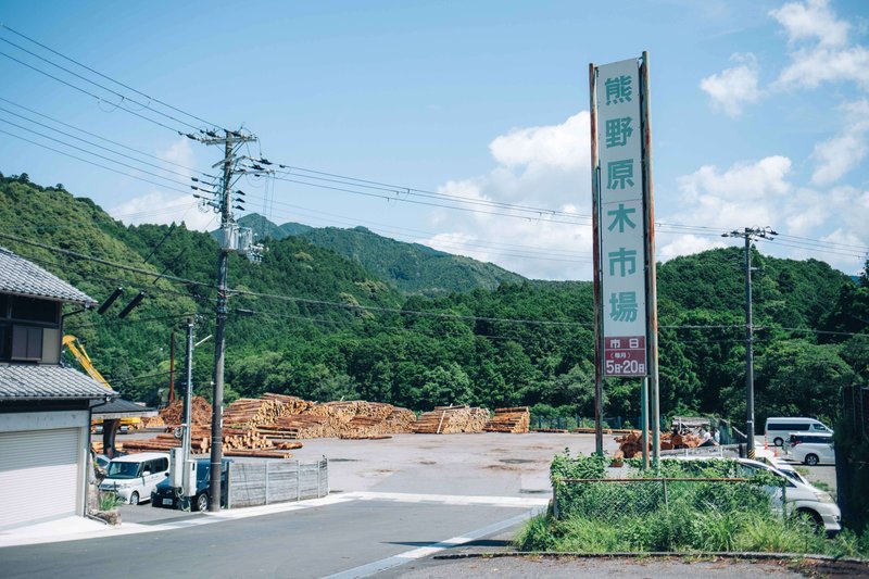 熊野原木市場の外観がわかる写真。広大なスペースに丸太が積み重なって並べられている