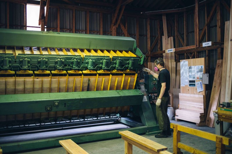 木材を圧着する機械とそれを操作するnojimoku様の社員。