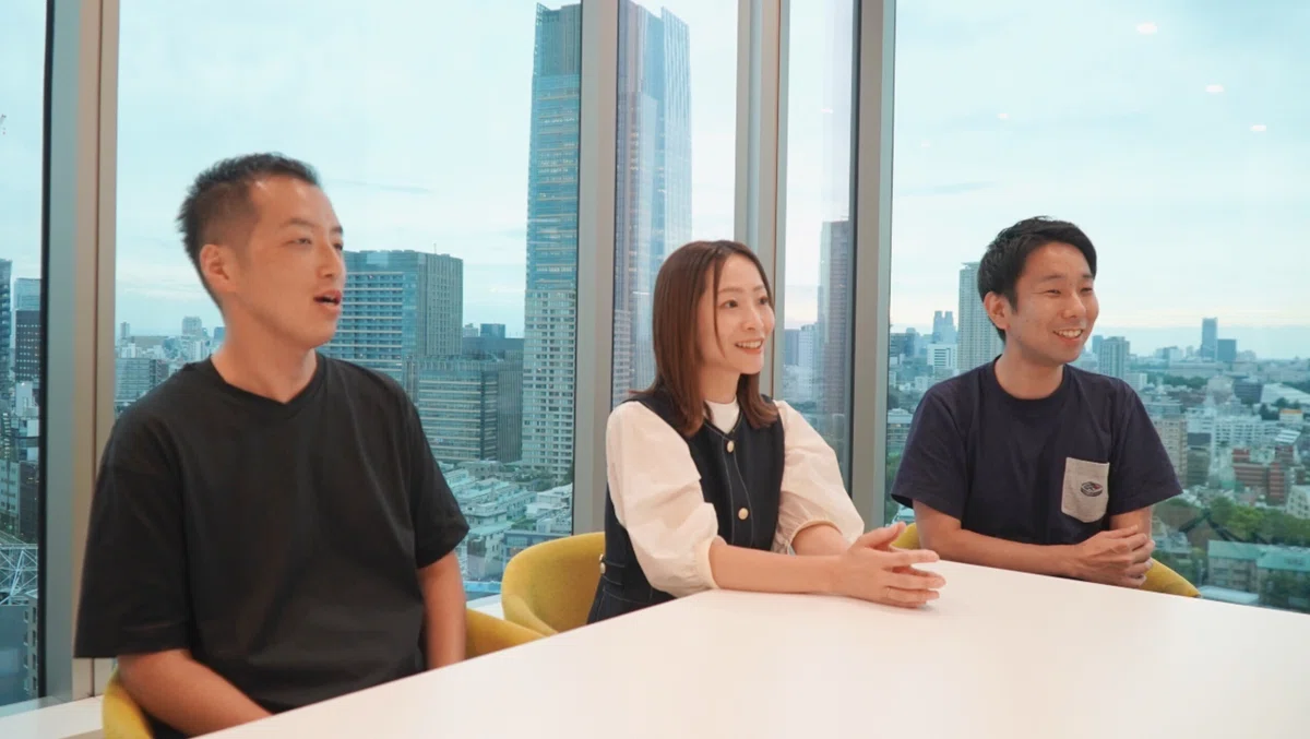 右側を向いて男性・女性・男性の順に並んで座った3人の写真。