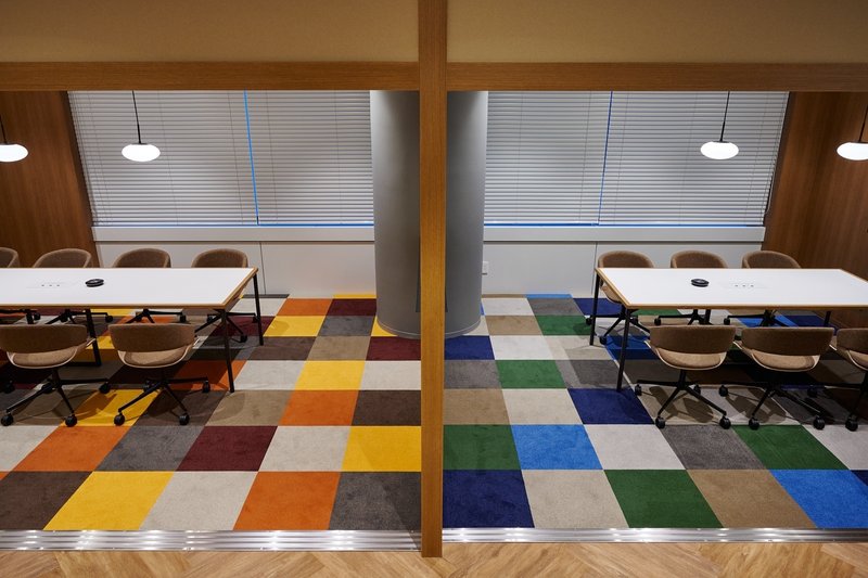 暖色と寒色のモザイクタイルのような床の会議室が2つ並んでいる写真。