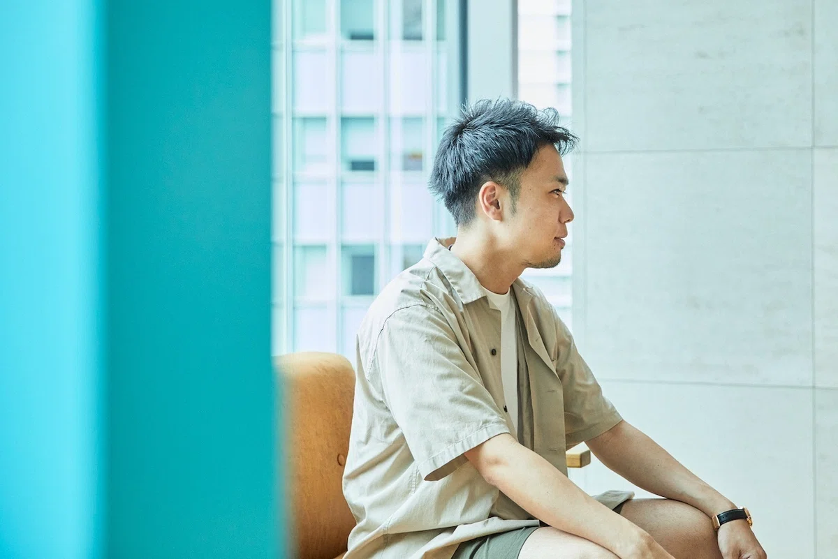 右側を向いて座る男性の写真。