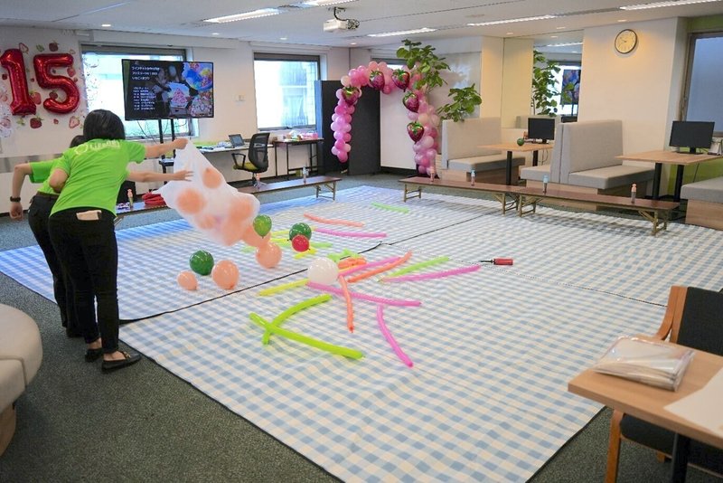 オフィス内にシートを敷き、風船で飾り付けをする社員たちの写真