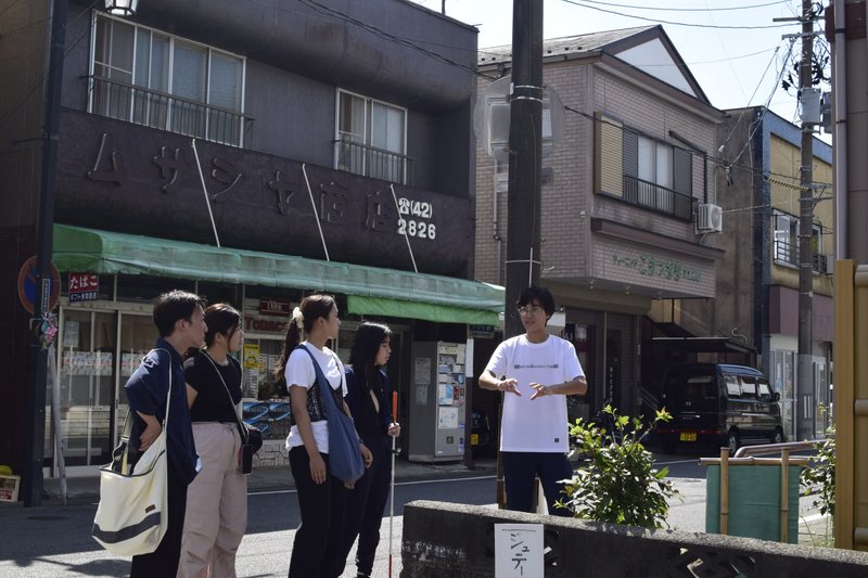 湯壺碑の前でまっきーが説明している　みんなまっきーの方をみて真剣に話を聞いている