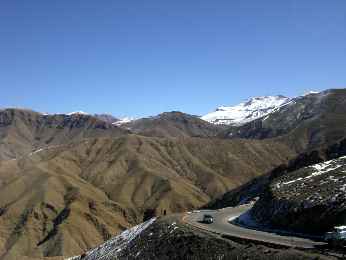 雪をかぶったアトラス山脈と木のない山々、それらの間を抜ける山道