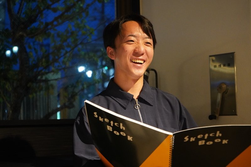三浦さんが発表している様子　笑顔でスケッチブックを持っている