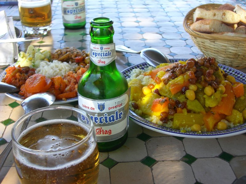 テーブルにのせられたビールと、野菜の煮物がのったライス、パン