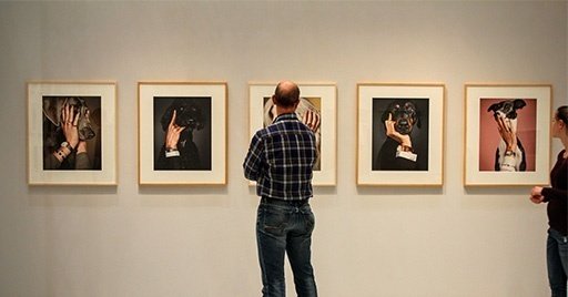 5枚の絵画を見つめる男性の後ろ姿