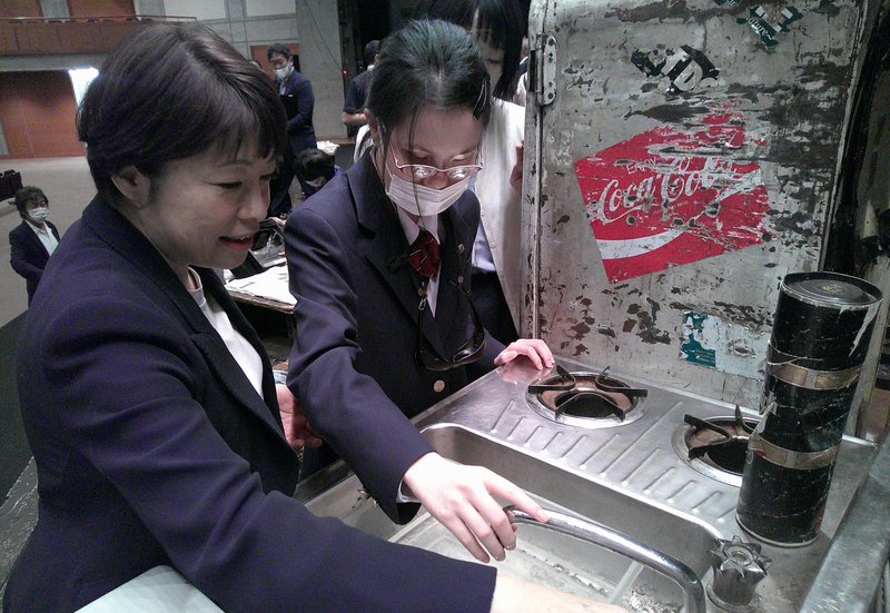 舞台手話通訳者の小島祐美さんとともに水道の蛇口を触って確かめています。