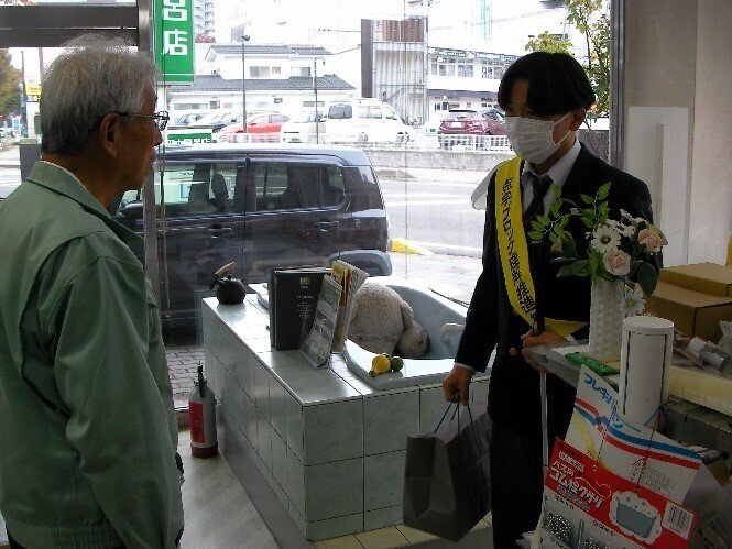 高等部の生徒が、田中風呂店さんにポケットティッシュを渡す様子