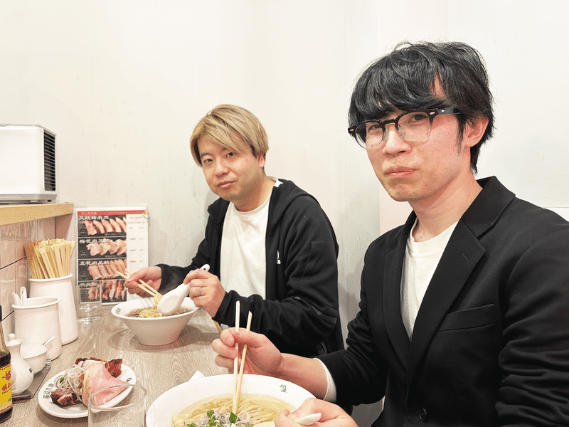 小島と伊藤が仲良くラーメンを食べている写真