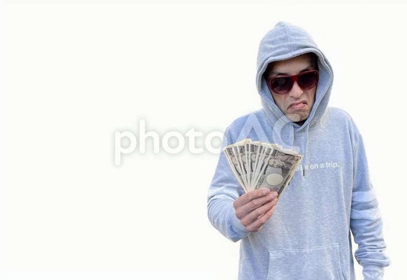 お金を持つパーカーのフードを被った日本人男性の画像