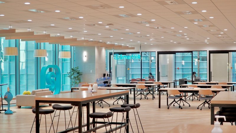SmartHRの東京オフィスフリースペースの写真。椅子と机が複数並んでおり、窓の外にはビルのガラス窓が見えている。