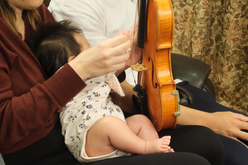 赤ちゃんがヴァイオリンの弦を触っている様子