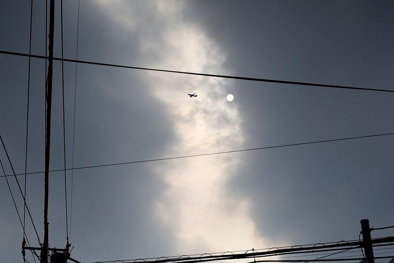 飛行機と雲越しの太陽と電線
