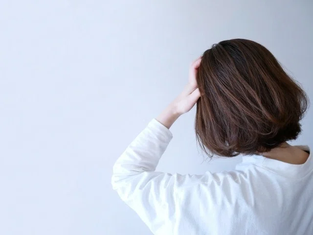 頭を抑える女性の後ろ姿